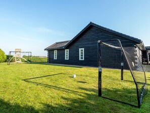 A wooden house with a fenced yard and a goalpost.