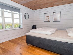 A bedroom with a bed, a window, and a wall-mounted clock.