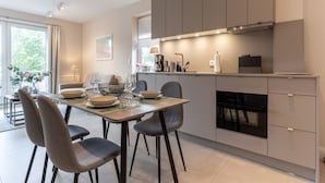 A modern kitchen with a dining area, featuring a large window, built-in cabinets, and a central island. - Renovierte Ferienwohnung, St. Peter-ording (St. Peter-Ording)
