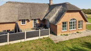 A thatched-roof cottage with a brick extension, outdoor seating, and a grassy yard. - 4 Star Holiday Home in Ulfborg (Ulfborg)