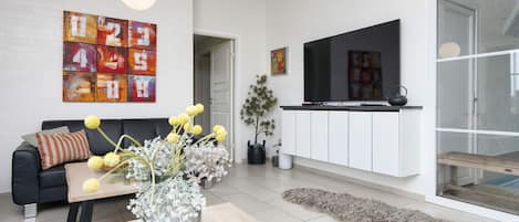 A modern living room with a sofa, coffee table, and a TV mounted on the wall.