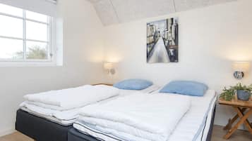 A bedroom with two beds, a window, a painting, and bedside lamps.