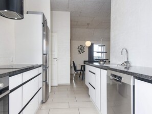 A modern kitchen with a stainless steel refrigerator, a built-in dishwasher, and a black countertop. - 4 Star Holiday Home in Ulfborg (Ulfborg)