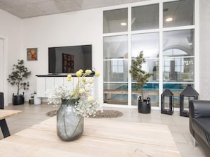 A modern interior with a large window, a fireplace, and a dining area. - 4 Star Holiday Home in Ulfborg (Ulfborg)