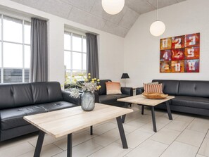 A modern living room with a black leather sofa, a wooden coffee table, and a decorative vase. - 4 Star Holiday Home in Ulfborg (Ulfborg)