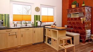 A modern kitchen with wooden cabinets, a sink, and a window with blinds. - Doppelhaushaelfte, Tankenhagen (Dassow)