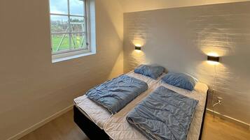 Un dormitorio con dos camas, una ventana e iluminación en la pared.