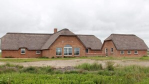 A large brick building with a thatched roof, a central arched doorway, and multiple windows. - 4 Star Holiday Home in Ulfborg (Ulfborg)