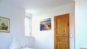 A bedroom with a bed, a wooden door, and two framed pictures on the wall. - Apartment for up to 6 People in Lepels Hof (Luetow)