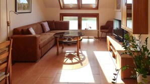 A living room with a brown sofa, a glass coffee table, a TV, and a wooden cabinet. - Apartment for up to 6 People in Lepels Hof (Luetow)