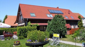 A building with a red tiled roof, solar panels, and a sign indicating a restaurant. - Apartment for up to 6 People in Lepels Hof (Luetow)