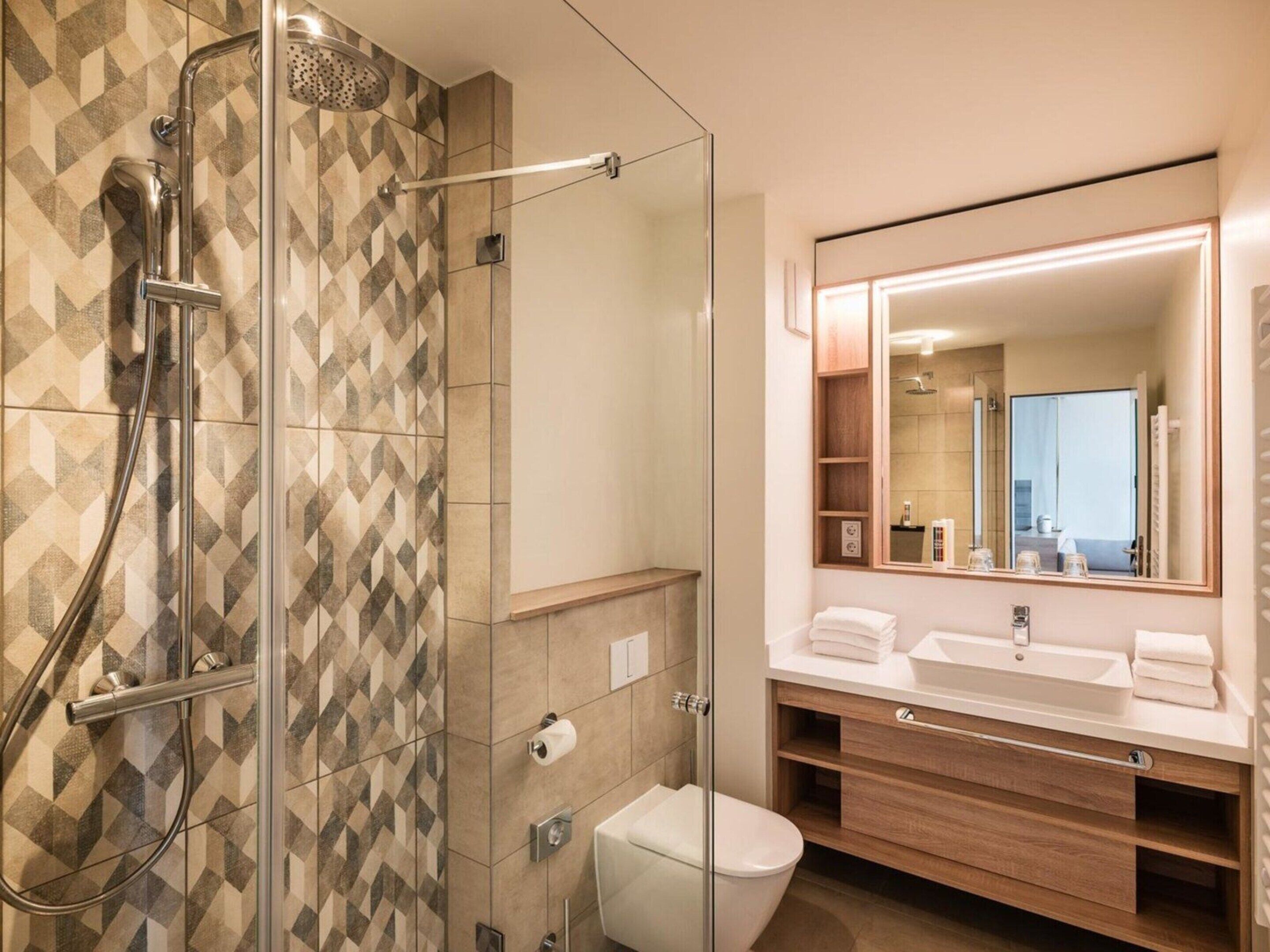 Un bagno moderno con doccia, servizi igienici e lavandino.