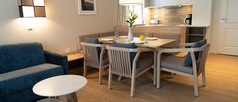 A modern living room with a sofa, a dining table with chairs, and a small round table.