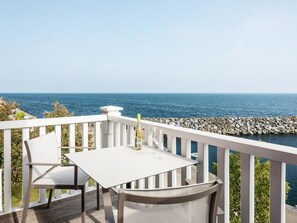 A deck with a white table and chairs overlooking the sea. - Beech Resort Boltenhagen (Boltenhagen)