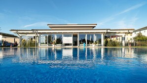 A swimming pool with a covered area and a building in the background.