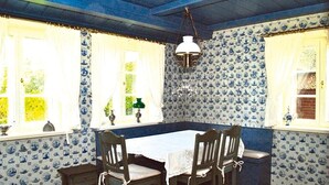 Une salle à manger avec une table et des chaises, un papier peint à motifs et un luminaire suspendu.