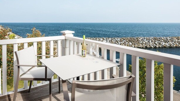 A deck with a white table and chairs overlooking the sea. - Beech Resort Boltenhagen (Boltenhagen)