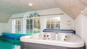Een bubbelbad in een kamer met uitzicht op een zwembad en een groot raam.