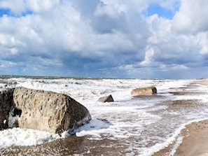 Paesaggio costiero con formazioni rocciose imponenti e una spiaggia sabbiosa.
