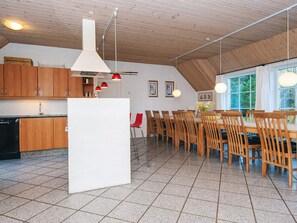 Et moderne køkken med træskabe, en hvid ø og røde hængelamper.