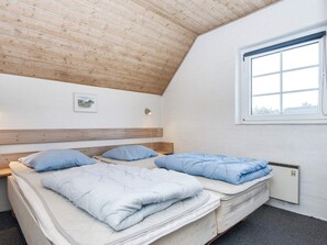 A bedroom with two beds, a wooden ceiling, a window, and a wall-mounted light. - 4 Star Holiday Home in Harboore (Harboore)