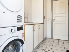 A laundry area with a washing machine, cabinets, and a door. - 4 Star Holiday Home in Harboore (Harboore)