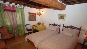 Ein Schlafzimmer mit zwei hölzernen Betten, einer Kristallleuchter, einem Tisch mit Lampe, einem Sessel und einem Teppich mit Blumenmuster.