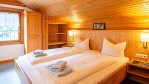 Ein Zimmer in einer Holzhütte mit einem Bett, zwei Nachttischen, einem Fenster und einem an der Wand hängenden Bild.