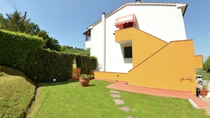 A white building with a yellow accent, a small porch, and a well-maintained lawn. - Holiday Home in Lucca With Pool & Garden (Capannori)