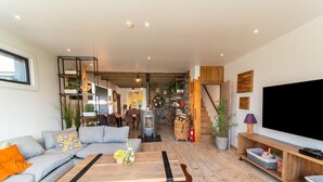 Un salon moderne avec un canapé, une table basse et un téléviseur. On y trouve également une cheminée, un plancher en bois et un escalier menant à un autre niveau.