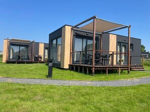 A modern, two-story house with large windows and a deck. - Modern House With a Beautiful View of Friesland (Menaldum)