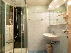 A modern bathroom with a glass-enclosed shower, a white sink, and a mirror with a towel rack. - Holiday Home in Gaschurn Near Town Center (Gaschurn)