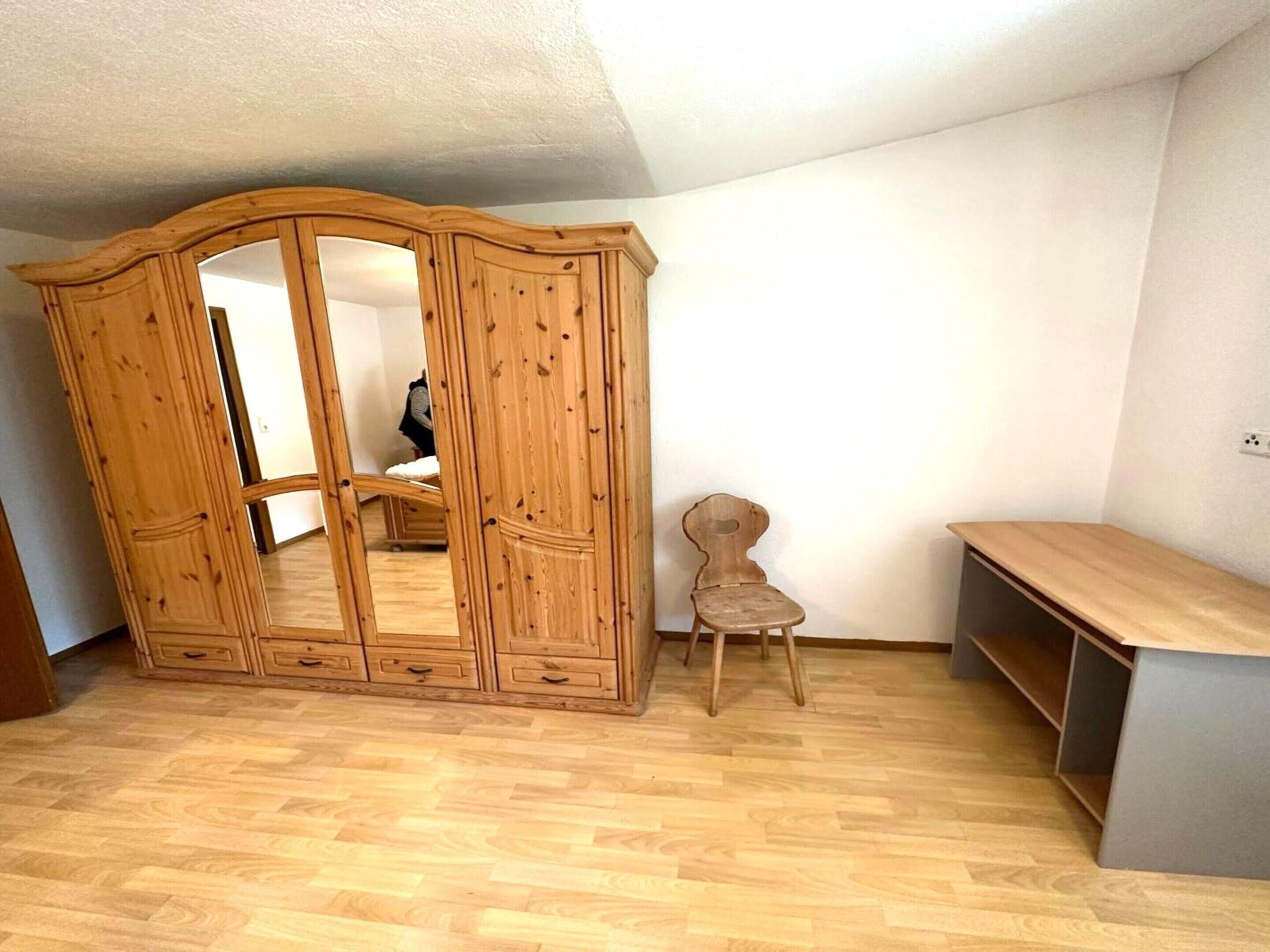 Une pièce comprenant une armoire en bois, une petite chaise en bois et un banc.
