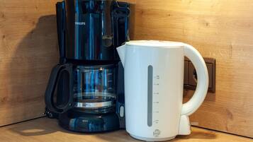 A coffee maker and a white mug on a wooden surface.