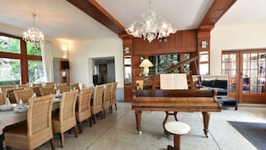 A dining area with a piano, wicker chairs, and a chandelier. - Sun & Sand Group Getaway (De Panne)