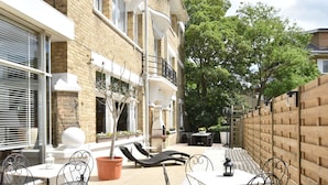 A courtyard with outdoor seating, a potted tree, and a brick building. - Sun & Sand Group Getaway (De Panne)