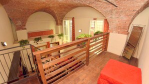 A loft-style room with exposed brick ceilings, wooden railings, and a red cushion. - Apartment in the Historic Center of Lucca (Lucca)