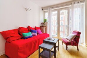 Ein modernes Wohnzimmer mit einem roten Sofa, einem kleinen Tisch und einem gestreiften Sessel.