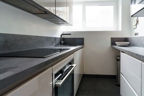A modern kitchen with a black countertop, stainless steel sink, and a window above the sink. - PARI-PEC534 Summary: (Paris)