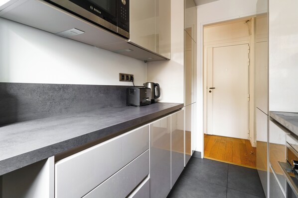 A modern kitchen with a black countertop, white cabinets, and a Bosch microwave.