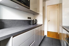 Eine moderne Küche mit schwarzer Arbeitsplatte, weißen Schränken und einer Bosch Mikrowelle.