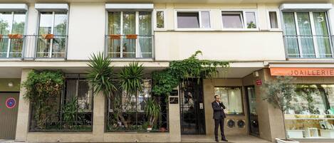 Un edificio con escaparate, un hombre de pie frente a él, y un letrero que dice 'JOAIELERIE'.