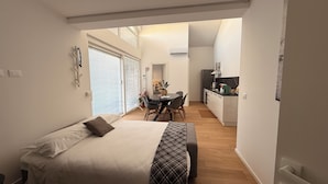 A compact bedroom with a bed, bedside table, and a window with blinds.