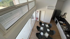 A modern kitchen with a dining area, large windows, and a view of the outdoors.