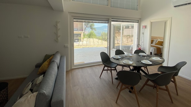 A dining area with a high ceiling, large windows, and a view of the outdoors.
