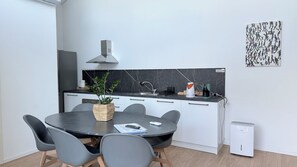 A modern kitchen with a dining area, a built-in stove, and a coffee maker.