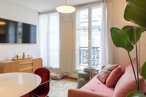 Un salon moderne avec un canapé, une table à manger et un téléviseur fixé au mur.