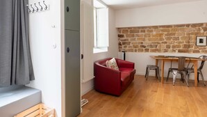 Ein gemütlicher Wohnbereich mit einem roten Sofa, einem Holzespeisetisch mit Stühlen, einer Steinwand und einem Fenster mit Vorhängen.