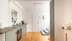 Eine kleine Küche mit Holzboden, Einbauofen und Kaffeemaschine.