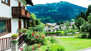 A traditional Alpine-style building with a balcony, surrounded by lush greenery and a mountain backdrop. - Spacious House In Fugen With Terrace (Fuegen)